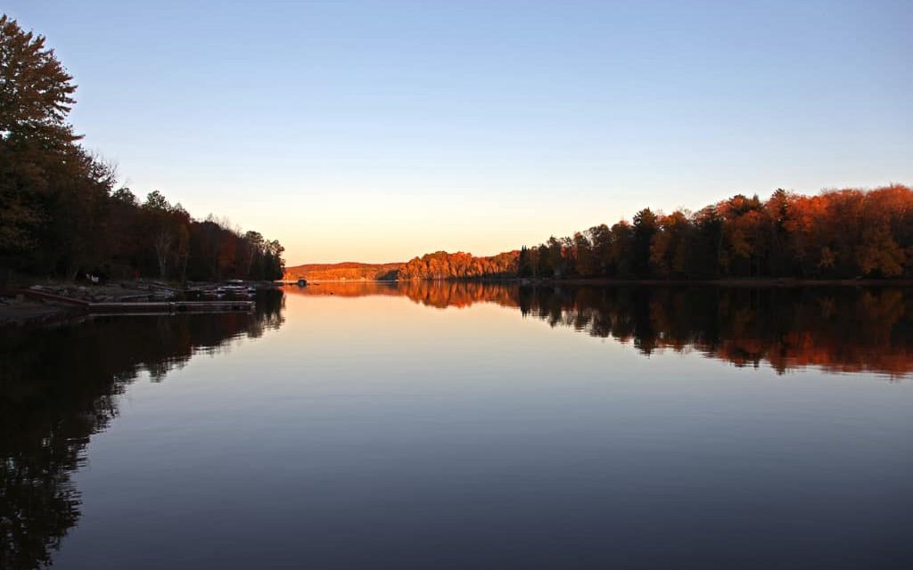 Sunrise shines on distant hills and calm Kawagama Lake.