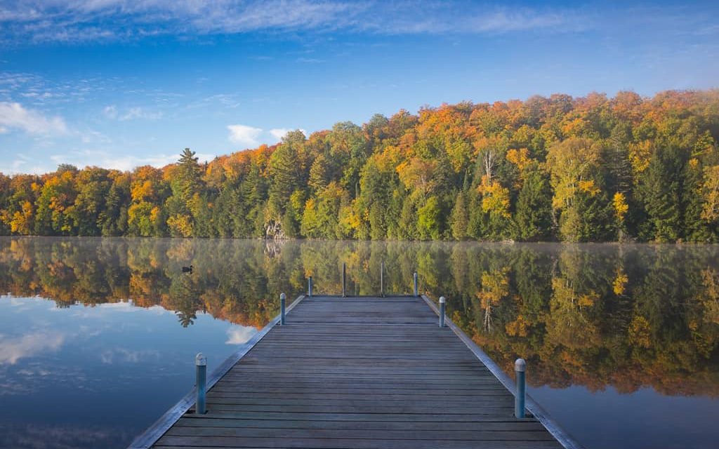 Beautiful fall colour foliage reflecting on a very still Lake Muskoka.