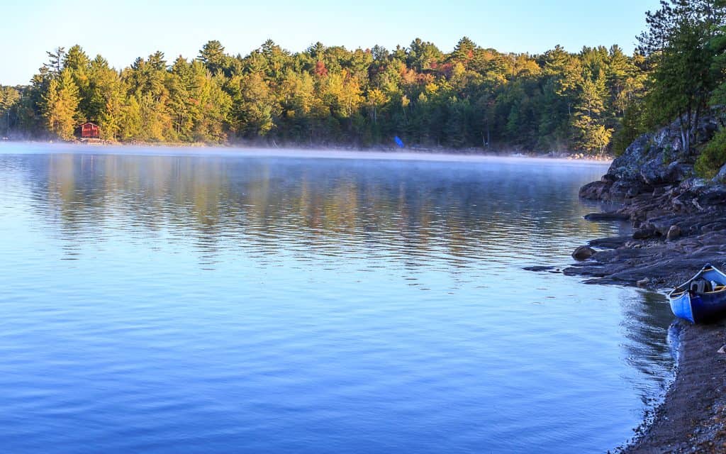 Misty water with a canoe on the shoreline of Sparrow Lake.